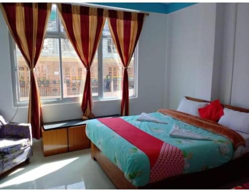 a bedroom with a bed and a large window at Hotel Snowland, Tawang in Tawang