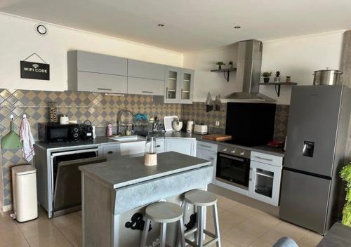 La cuisine est équipée d'un réfrigérateur et d'un comptoir avec tabourets. dans l'établissement Maison Calenzana, à Calenzana