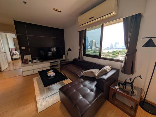 a living room with a leather couch and a large window at High Floor Great View 2BR 2BA 3 mins to Nana BTS in Bangkok