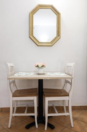 Una mesa con dos sillas y un espejo en la pared. en Casa Lollobrigida, en Ciampino