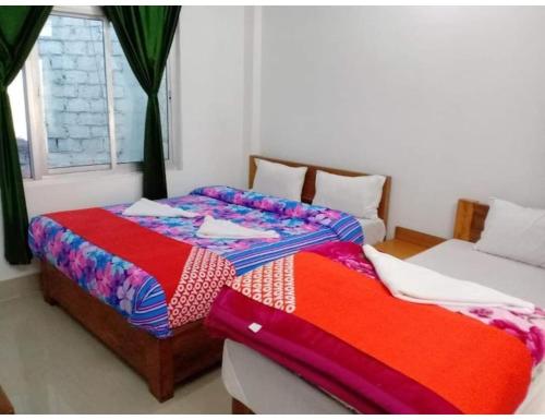 a bedroom with two beds and a window at Hotel Snowland, Tawang in Tawang