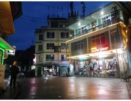 a man standing in front of a building at night at Hotel Snowland, Tawang in Tawang