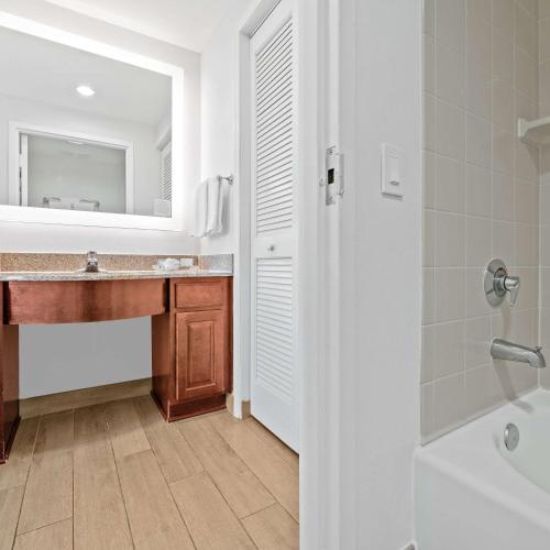 a bathroom with a sink and a mirror and a tub at Homewood Suites by Hilton Fort Lauderdale Airport-Cruise Port in Dania Beach