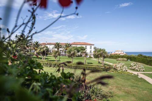 a house with palm trees and the ocean in the background at Hôtel La Réserve in Saint-Jean-de-Luz
