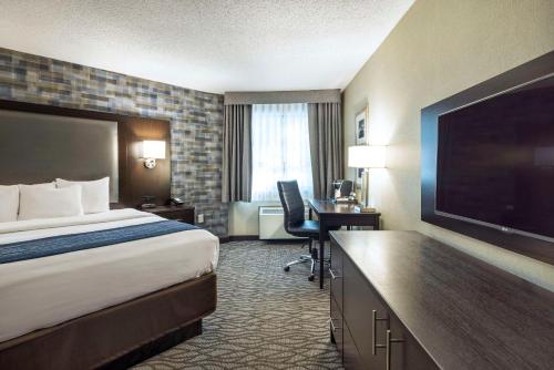 a hotel room with a bed and a flat screen tv at Comfort Inn Montreal Aeroport in Pointe-Claire