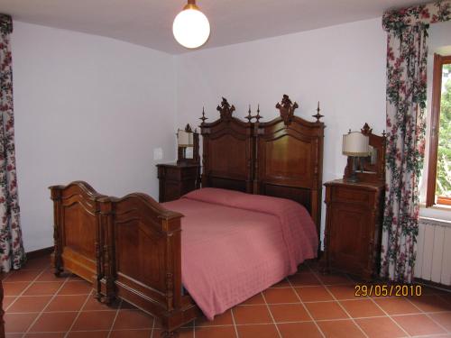 a bedroom with a wooden bed with a red blanket at Podere Suvignano in Murlo