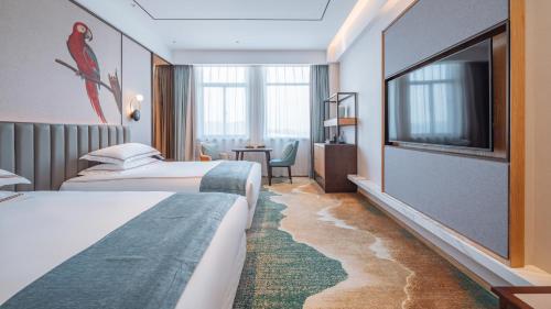 a hotel room with two beds and a flat screen tv at Wellay Hotel Ningbo Jiangbei Olympic Sports Center in Ningbo