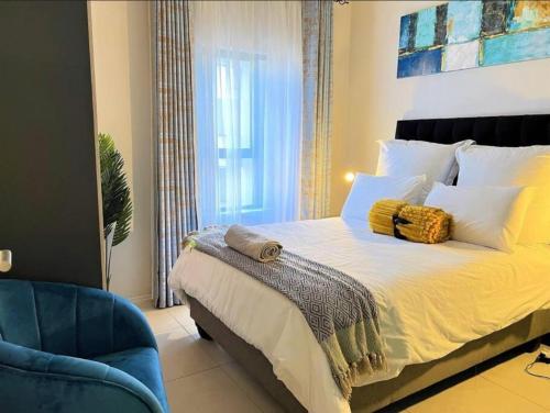 a bedroom with a large bed and a blue chair at Exquisite Classy 1 bed in Midrand at 93 on New Lifestyle Estate in Midrand