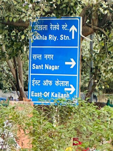 a blue street sign with writing on it at Luxury HomeStay Prime Location, South Delhi in New Delhi