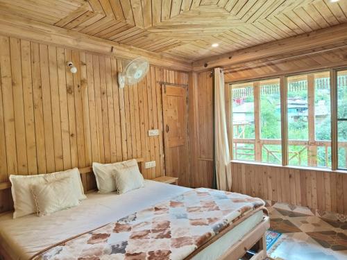a bedroom with a bed in a wooden room at Tirthan Majestic View Homestay in Gushaini