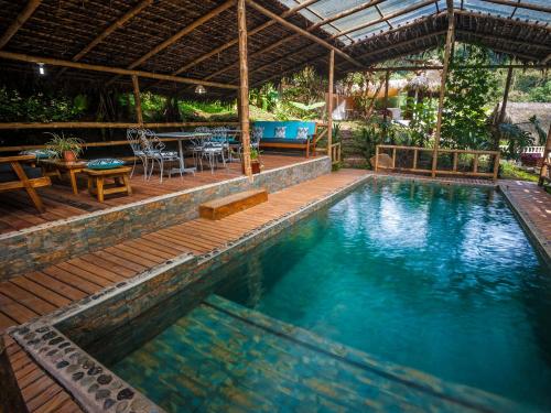 una piscina con terraza, mesa y sillas en El Septimo Paraiso, en Mindo