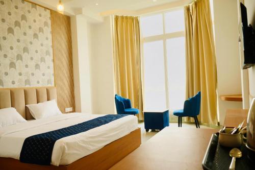 JaunpurHotel JMS Grand的酒店客房,配有一张床和两张蓝色椅子