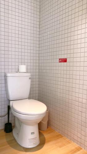 a bathroom with a toilet in a white tiled wall at Sleep jia in Tainan