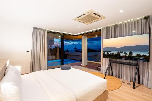 a bedroom with a large white bed and a balcony at Villa Serenity Bay, Modern 4-BR Partial Sea View villa in Plai Laem