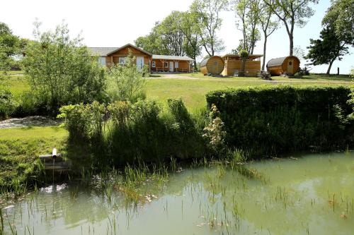 vista su un laghetto con una casa sullo sfondo di Peenehof Köppen - Schlaffässer Hannah oder Jette a Jördenstorf
