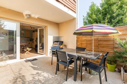 une terrasse avec une table, un parasol et des chaises dans l'établissement Beautiful apartment, terrace and garden, close to beaches, à Lit-et-Mixe
