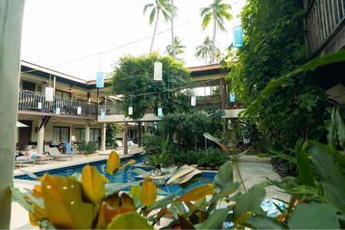 a hotel with a swimming pool with people sitting in it at Vacation Village Phra Nang Inn - SHA Extra Plus in Ao Nang Beach