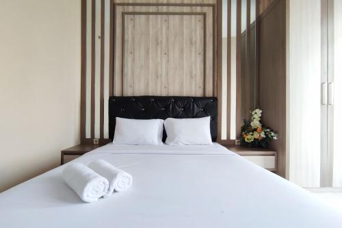Una cama blanca grande con dos toallas encima. en Comfortable and Modern 1BR without Living Room at Amartha View Apartment By Travelio, en Semarang