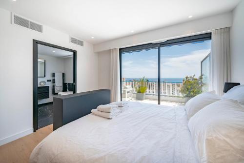 - une chambre avec un grand lit blanc et une grande fenêtre dans l'établissement Suite Horizon Penthouse d'exception avec Vue Mer à Cannes, à Cannes