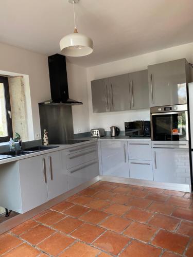 a kitchen with white cabinets and a tile floor at Le gîte de Mauvielle in Solomiac