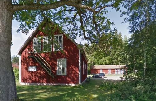 a red barn with a tree in front of it at Tivedens Hostel-Vandrarhem in Karlsborg