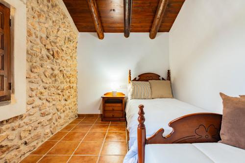 a bedroom with a bed and a stone wall at Mas de Morera in Vall dʼAlba