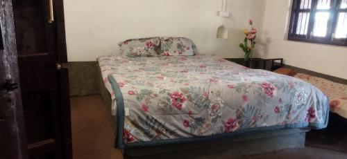 Un dormitorio con una cama con una colcha floral. en OUR FARM Agro-Eco Tourism and Farm Stay, en Helwāk