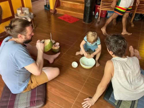 a man and two children sitting on the floor at โฮมสเตย์บ้านนายสิงโตเขาคูหา in Ban Khu Ha Nai (1)