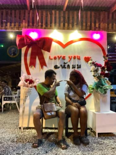 a man and a woman sitting in front of a sign at โฮมสเตย์บ้านนายสิงโตเขาคูหา in Ban Khu Ha Nai (1)