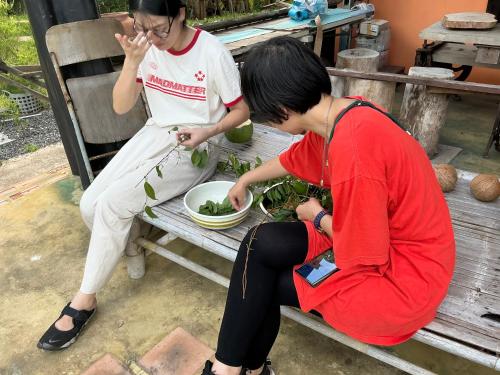 two people sitting on a bench with a bowl of food at โฮมสเตย์บ้านนายสิงโตเขาคูหา in Ban Khu Ha Nai (1)
