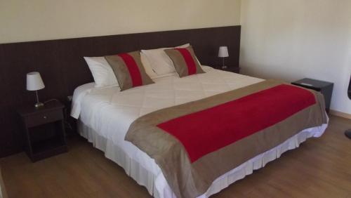 a bedroom with a large bed with a red and white blanket at Vitrali Suite in Copiapó