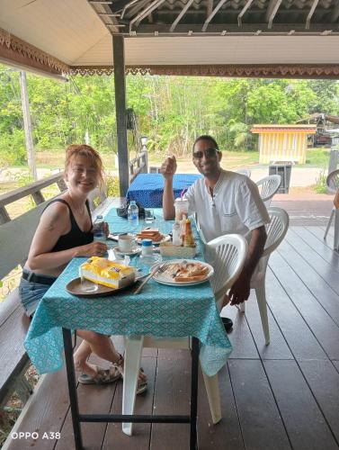a man and woman sitting at a table with food at Phetmanee Resort in Ko Yao Noi