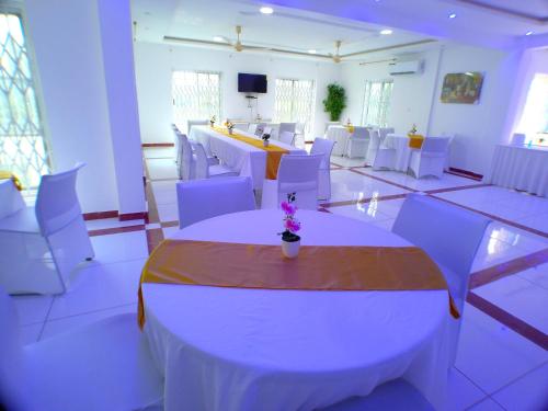 a banquet hall with white tables and white chairs at Park Springs Hotel in Cape Coast
