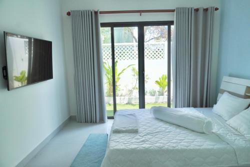 a bedroom with a white bed and a sliding glass door at Shin's House Cozy & Green Space in Phu Quoc