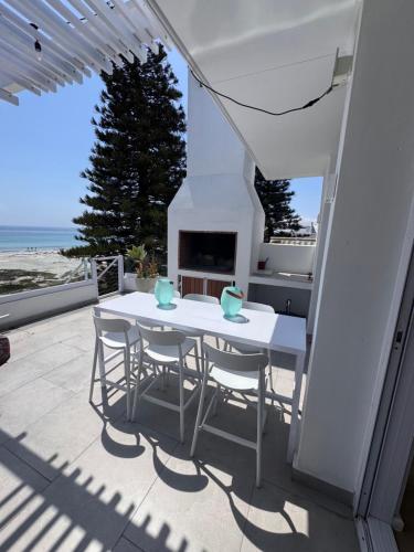 a white table and chairs on a patio with a fireplace at Sunset Shores in Lambertʼs Bay