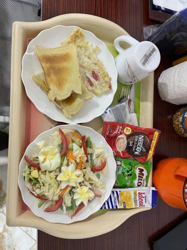 two plates of food on a tray with salad and toast at Park Springs Hotel in Cape Coast