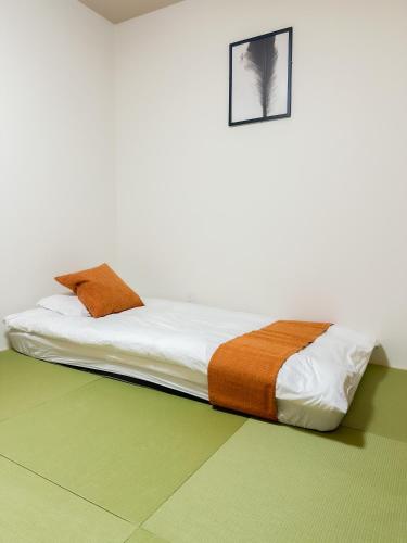 a bed in a white room with avertisement for at HANASTAY花渓居 · 海（UMI) in Osaka