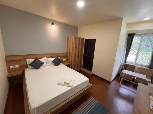 a bedroom with a bed and a table and a chair at Lamahatta Clouds Hotel & Restaurant in Takdāh