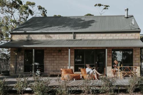 two women sitting on chairs in front of a building at Waterfront - Hot Tub - Sauna - Serenity in Coles Bay