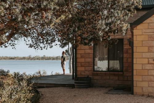 a man standing on the porch of a house at Waterfront - Hot Tub - Sauna - Serenity in Coles Bay