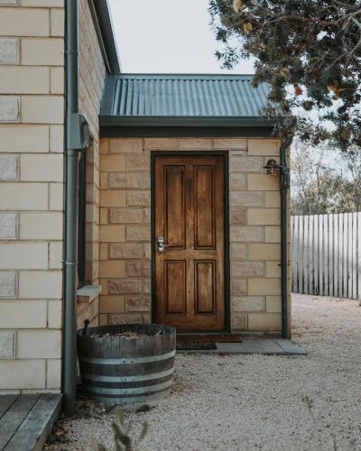 a small building with a wooden door and a barrel at Waterfront - Hot Tub - Sauna - Serenity in Coles Bay