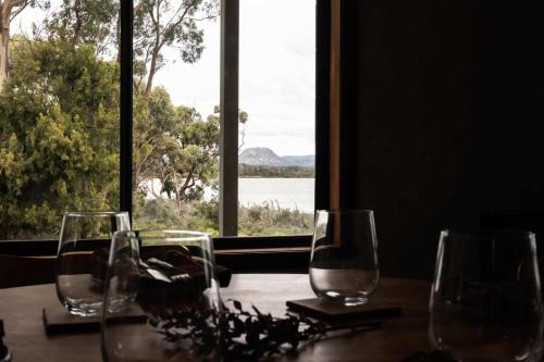 a table with three wine glasses and a window at Waterfront - Hot Tub - Sauna - Serenity in Coles Bay