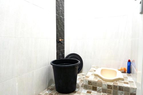 a bathroom with a toilet and a trash can at Palma Villa Bumi Dieng Indah in Kertosobo