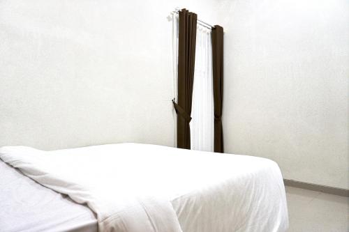 a bed in a room with a white sheet at Palma Villa Bumi Dieng Indah in Kertosobo