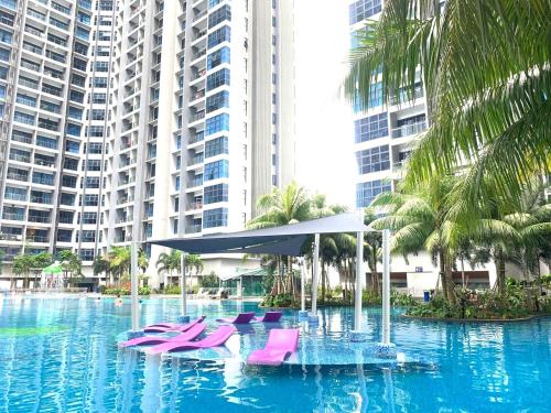 a hotel swimming pool with pink chairs and palm trees at Atlantis Residences Melaka in Melaka