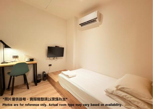 a small room with a bed and a desk with a computer at Let's Hostel in Kaohsiung