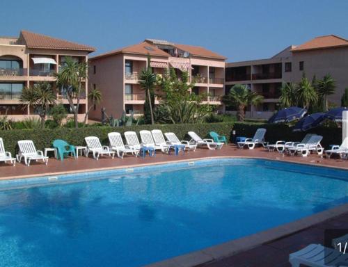 une piscine avec des chaises longues et un hôtel dans l'établissement Les Marines de Moriani, à San-Nicolao