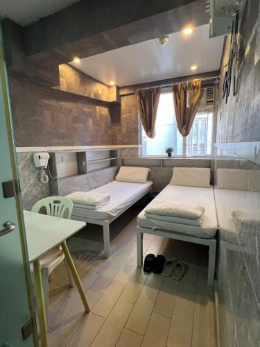 a room with two beds and a table at 168 Youth Hostel in Hong Kong