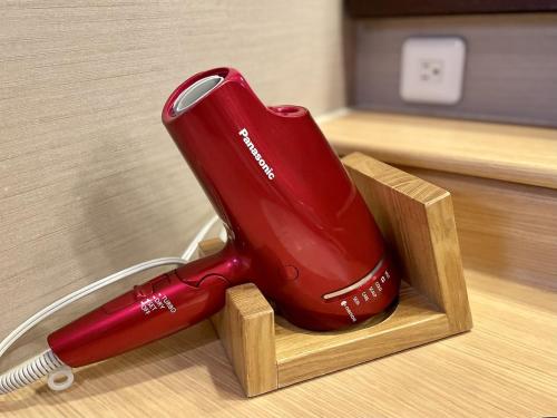 a red electric toothbrush sitting in a wooden holder at Dormy Inn Premium Wakayama Natural Hot Spring in Wakayama