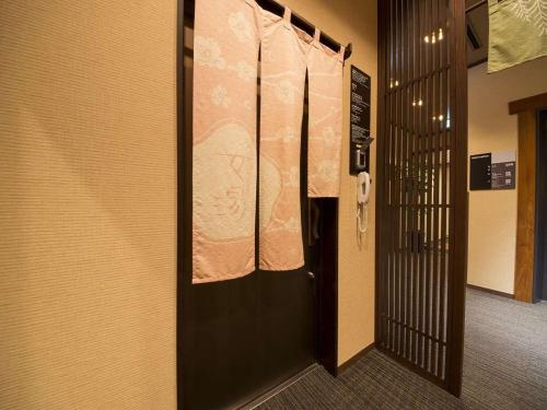 a corridor of a prison cell with a door and a phone at Dormy Inn Premium Wakayama Natural Hot Spring in Wakayama